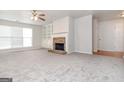 Spacious carpeted living room with a cozy brick fireplace and built-in shelving for storage and decor at 1716 Anniston Dr, Mcdonough, GA 30253