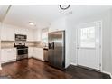 Modern kitchen with white cabinets, stainless steel appliances, granite countertops, and dark hardwood floors at 1590 Sw Cherry Hill Ln, Conyers, GA 30094