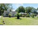 Lovely tree-lined street view of charming single story light blue home with green grass at 1774 Campbellton Rd, Atlanta, GA 30311