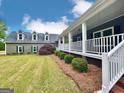 Home with long porch, manicured hedges and green lawn at 1040 Rock Creek Rd, Social Circle, GA 30025