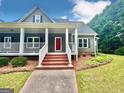 Charming home with brick stairs, a white porch and a vibrant red front door at 1040 Rock Creek Rd, Social Circle, GA 30025