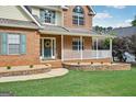 Close-up of a welcoming front porch with brick accents, a decorative wreath, and manicured landscaping at 612 Longer Dr, Peachtree City, GA 30269