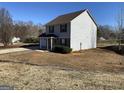 Side view of a two story home with gray siding, set against a backdrop of trees and sky at 253 Whistle Way, Locust Grove, GA 30248
