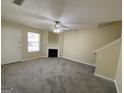 View of an empty living room featuring neutral paint, a fireplace, a ceiling fan, and carpeted floors at 253 Whistle Way, Locust Grove, GA 30248