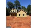 New home construction with light yellow siding and a classic gable roof design in a wooded area at 107 Oak Rd, Locust Grove, GA 30248