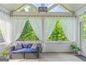 Relaxing sunroom with a comfortable seating area, airy curtains, and views of the lush greenery at 19 Mediterranean Ave # 506, Sharpsburg, GA 30277