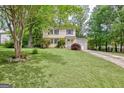 Traditional two-story home with yellow siding, manicured lawn, and a paved driveway leading to the garage at 131 Sweetgum Rd, Peachtree City, GA 30269