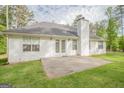Spacious backyard features concrete patio and lush lawn with a white house and brick chimney in the background at 2180 Briarwood Ct, Villa Rica, GA 30180