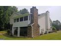 View of a home's rear exterior, highlighting a stone chimney and a screened-in porch at 2477 Briar Valley Way, Dacula, GA 30019
