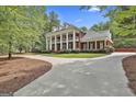 Grand two-story brick home with a striking columned facade, circular driveway and lush landscaping at 602 Embassy Ct, Peachtree City, GA 30269