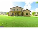 Expansive backyard features a well-manicured lawn, covered patio, and brick exterior of the home at 2589 Lake Erma Dr, Hampton, GA 30228