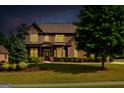 Charming two-story brick house with manicured landscaping and illuminated windows offering a welcoming ambiance at dusk at 2589 Lake Erma Dr, Hampton, GA 30228