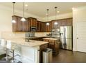 Well-lit kitchen boasts wooden cabinetry, stainless steel appliances, granite countertops and breakfast bar at 2589 Lake Erma Dr, Hampton, GA 30228