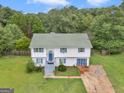 Charming two-story home with a green shingled roof, nestled among lush trees, and a driveway at 140 Joshua St, Palmetto, GA 30268
