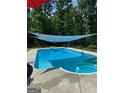 Sparkling swimming pool with shade covering provides a serene outdoor oasis at 57 Deer Creek Run, Moreland, GA 30259