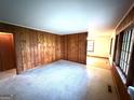 Spacious living room featuring wood paneling, neutral carpeting, and ample natural light from the windows at 359 Keys Ferry St, Mcdonough, GA 30253