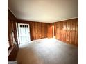 Inviting living room with wood paneling, white front door, neutral carpeting, and large windows at 359 Keys Ferry St, Mcdonough, GA 30253