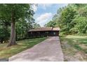 A charming single story home with a covered porch and long driveway surrounded by lush trees at 134 Ashwood Dr, Waco, GA 30182