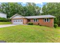 A charming brick home featuring an attached garage and a lush, green front lawn at 295 Merrydale Dr, Fayetteville, GA 30215
