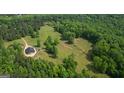 Aerial shot of the wooded property featuring a modern home, grassy fields, and natural beauty at 9511 High Point Rd, Villa Rica, GA 30180