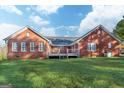 Rear view of a brick home with a cozy deck and a well-maintained yard at 7963 Smith Rd, Villa Rica, GA 30180