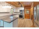 Well-lit kitchen with white cabinets, stainless steel appliances, granite countertops, and wood flooring at 1597 Leguin Mill Rd, Locust Grove, GA 30248