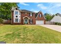 Traditional brick home featuring a lush green lawn, a welcoming light blue door, and a two-car garage at 317 Calgary Dr, Peachtree City, GA 30269