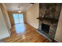 Bright living room with hardwood floors and a stone fireplace with sliding glass doors to a deck at 5128 Running Fox Trl, Norcross, GA 30071