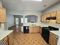 Open kitchen with black appliances, wooden cabinets, and tile floors overlooking the living room at 6206 Flat Trace, South Fulton, GA 30291