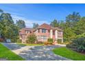 Well-maintained brick residence with a circular driveway and lush landscaping, set against a backdrop of mature trees at 7523 Kimberly Lynn Ct, Lithonia, GA 30058