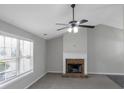 Bright living room featuring a brick fireplace, plush carpeting, and a large window at 90 Heatherstone Way, Covington, GA 30016
