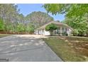 Long driveway leading to a cozy house with a well-kept lawn and a backdrop of mature trees at 15 Riverside Pkwy, Sharpsburg, GA 30277