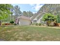 Well-maintained home with a lush green lawn, complemented by mature trees and a serene outdoor setting at 15 Riverside Pkwy, Sharpsburg, GA 30277