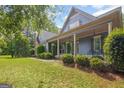 Charming blue home featuring an inviting front porch with classic columns, green bushes, and a lush green lawn at 68 Timber Creek Estates Dr, Sharpsburg, GA 30277