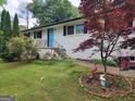 Lovely front yard featuring a well-maintained lawn, and mature trees surrounding a white painted brick home with a blue door at 3969 W Hilda Cir, Decatur, GA 30035