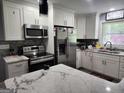 Modern kitchen with stainless steel appliances, marble countertops, sleek white cabinets, and stylish gray backsplash at 3969 W Hilda Cir, Decatur, GA 30035