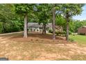 View of a quaint home through several trees and a yard covered in pine straw at 372 River Point Dr, Mcdonough, GA 30252