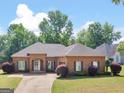 A brick home with manicured lawn and landscaping features a symmetrical façade and an attached garage at 570 Mcgarity Dr, Mcdonough, GA 30252