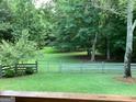 Large backyard featuring a well-maintained lawn, a fence, mature trees and lush greenery at 857 Cooper Rd, Social Circle, GA 30025