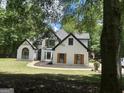 View of the home nestled among mature trees with a manicured lawn and American flag displayed at 857 Cooper Rd, Social Circle, GA 30025