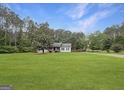 Single-story home sits on a large lawn surrounded by dense trees, offering privacy at 401 Grove Pointe Ct, Locust Grove, GA 30248