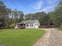 View of home with a long driveway, lush green lawn, and tall trees in the background at 401 Grove Pointe Ct, Locust Grove, GA 30248