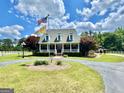 Beautiful home with a circular driveway, mature trees, a flagpole, and a covered front porch at 382 Knox Chapel Rd, Social Circle, GA 30025