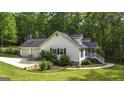 House with a two-car garage, manicured lawn, and stone-lined garden beds at 3180 Sweetbriar Dr, Villa Rica, GA 30180