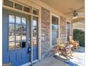 Inviting front porch featuring stone accents, ceiling fan, and comfortable rocking chairs at 1141 Pebble Creek Ln, Locust Grove, GA 30248