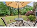 Inviting backyard patio setup with umbrella-covered table and chairs, perfect for outdoor relaxation at 243 Kensington Trce, Stockbridge, GA 30281