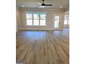 Open living room with large windows and a glass door, featuring hardwood floors and a ceiling fan at 1715 Crumbley Rd # 2, Mcdonough, GA 30252