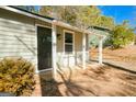 Covered front porch featuring white support beams and a dark screen door, flanked by mature landscaping at 8479 Alden Dr, Riverdale, GA 30274