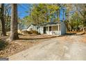 Well-kept single-story home with a covered porch and a concrete driveway surrounded by mature trees at 8479 Alden Dr, Riverdale, GA 30274