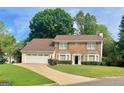 Charming two-story brick home with a manicured lawn and an attached two-car garage at 130 Floss Flower Ct, Roswell, GA 30076